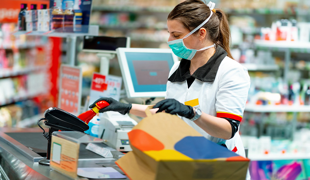featured image of a store clerk scanning groceries while wearing a mask and gloves