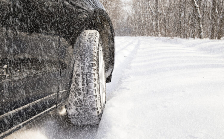 featured image showing a car driving in a snowstorm on an unplowed road