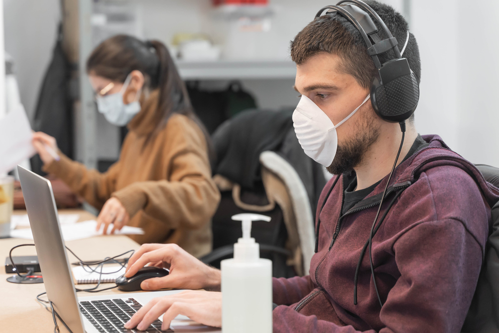 featured image showing employees wearing masks, working 6 feet apart with access to hand sanitizer