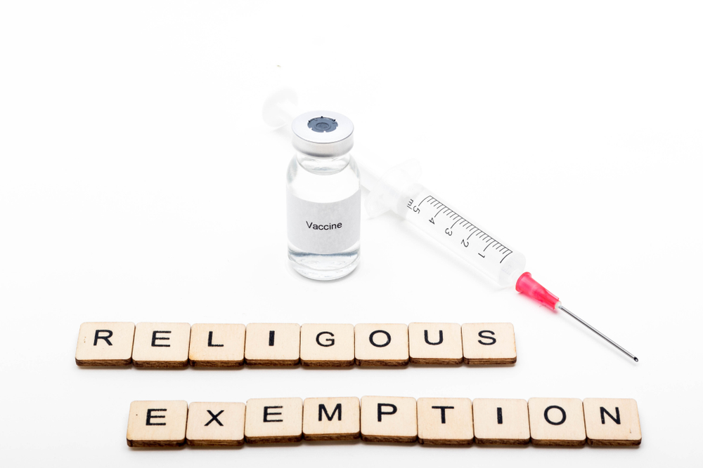 Featured image showing a medical vial with a Vaccine label on a white background along with a sign reading Religious Exemption